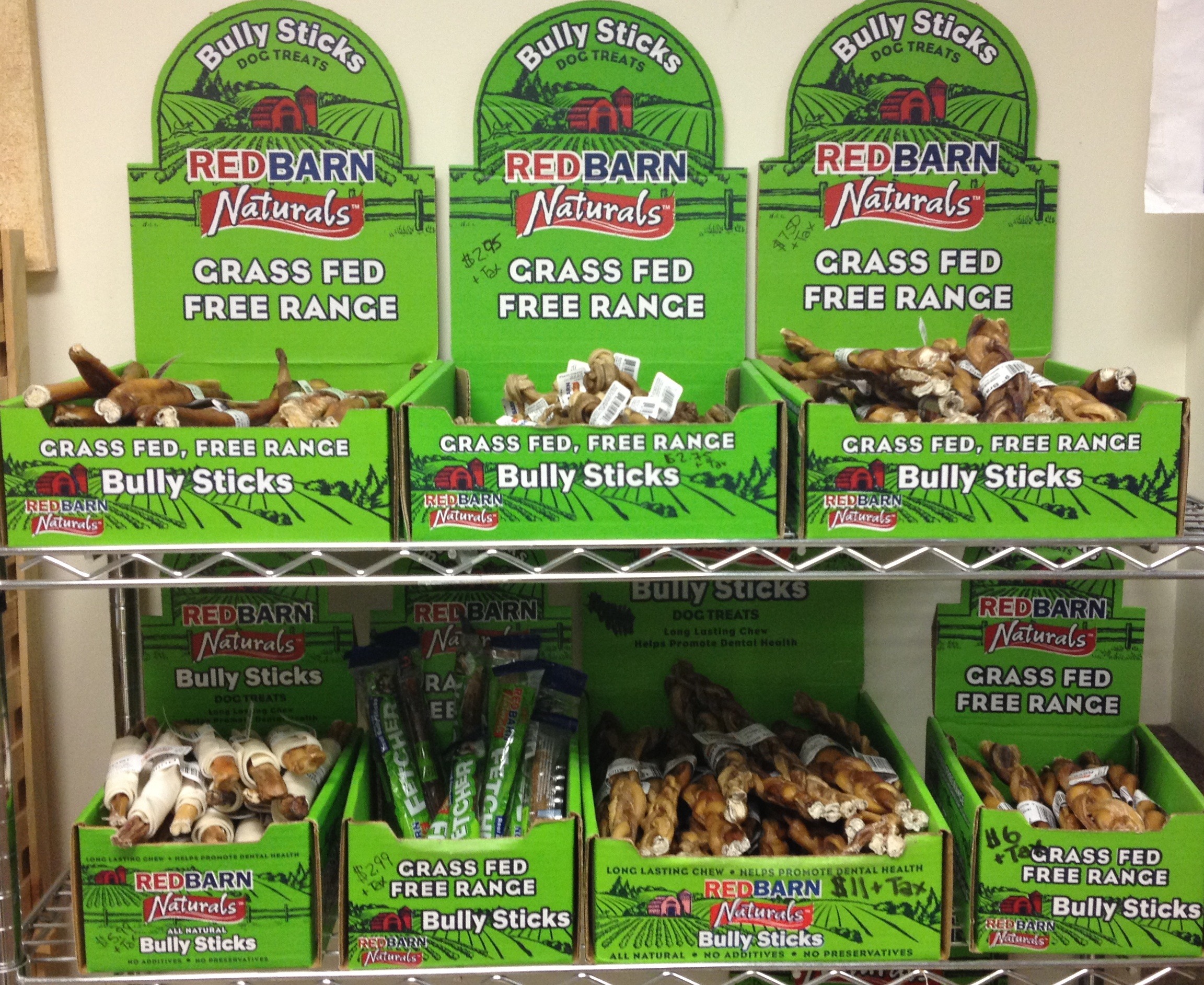 Rows of green boxes labeled "Redbarn Naturals Bully Sticks" showcase various dog chew treats, emphasizing grass-fed and free-range qualities.